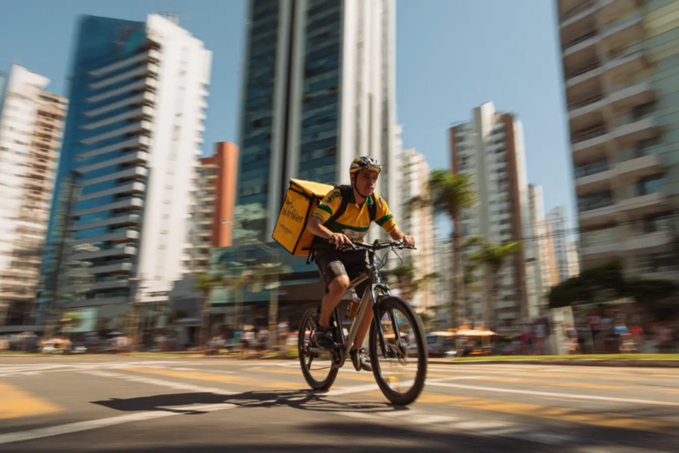 Entregador de bike em uma rua movimentada de cidade grande, mostrando quanto um entregador de bike ganha por dia