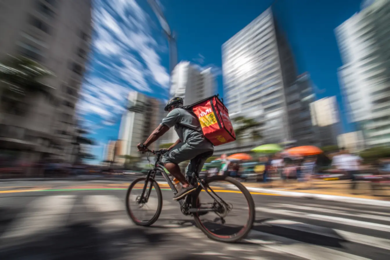 Entregador de bike olhando o celular com diversos aplicativos, pensando em quanto um entregador de bike ganha por dia