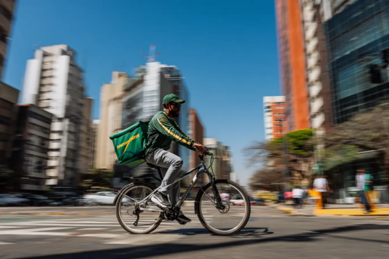 Entregador de bike sorrindo após uma entrega bem-sucedida, demonstrando quanto um entregador de bike ganha por dia